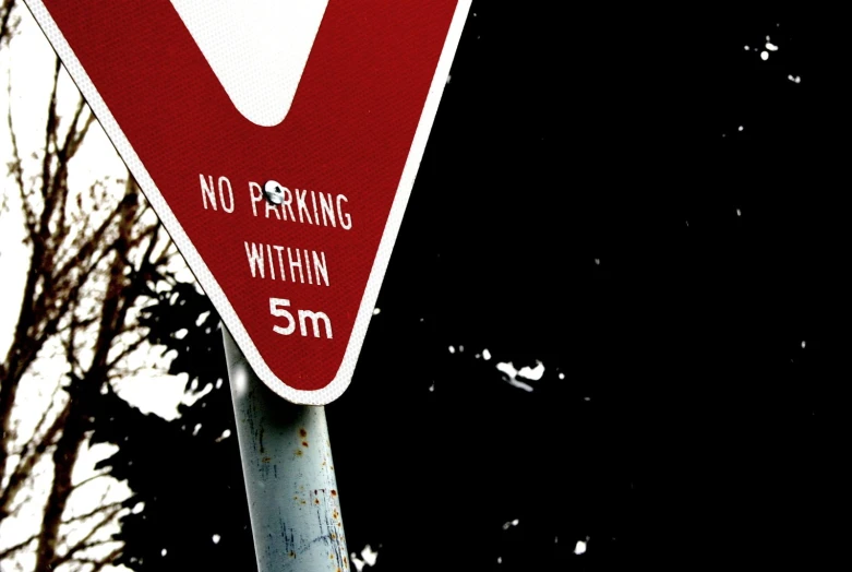 a red and white traffic sign in front of trees