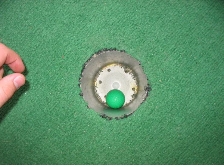 someone using an apple in a hole to put their golf balls