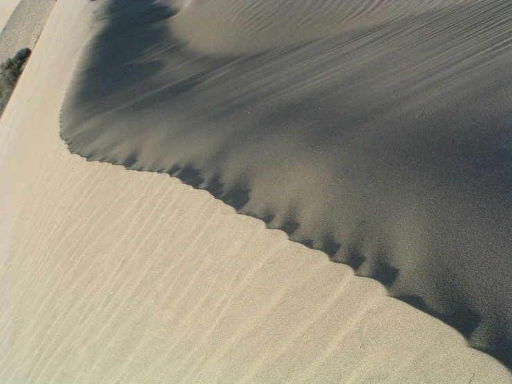 a sandy dune with ridges and footprints coming down into the sand