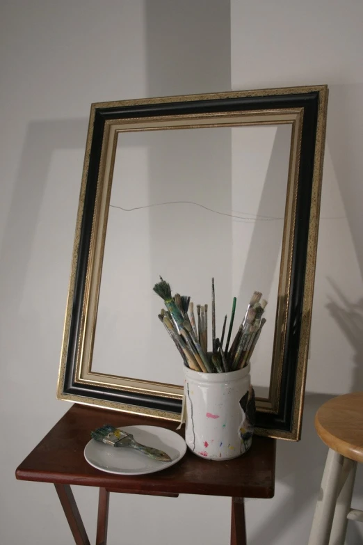 there is a framed pograph with paintbrushes on the table next to the brush