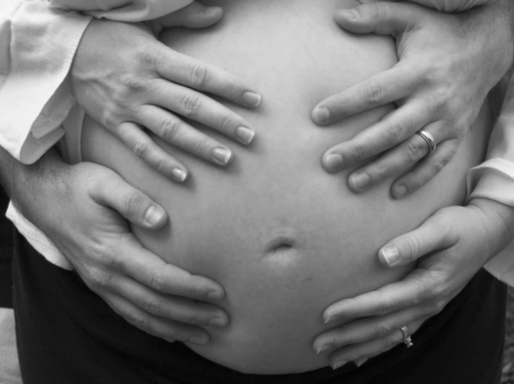 a close up of a pregnant woman with her hands on the stomach