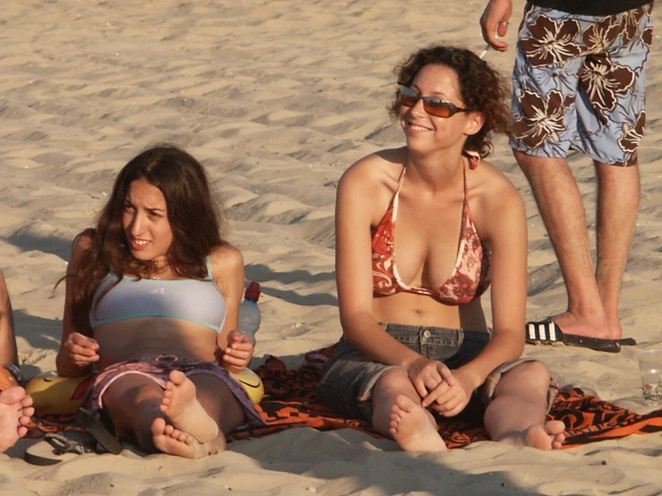two girls in bathing suits sitting on the beach