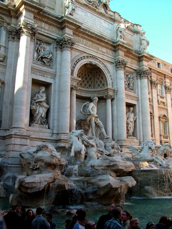 a group of people standing around an outdoor fountain