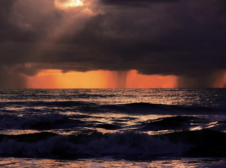 rain is coming over an ocean near the shore