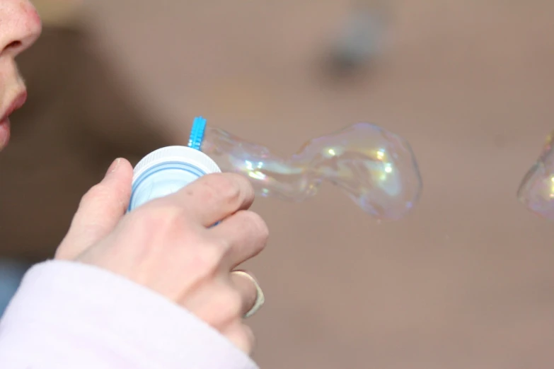 a woman is blowing bubbles from a bottle