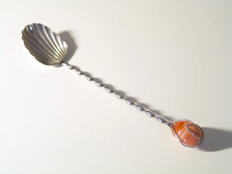 a metal spoon with a stone on the top of it