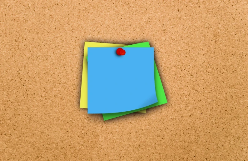 a piece of note paper and a pin sitting on a cork board