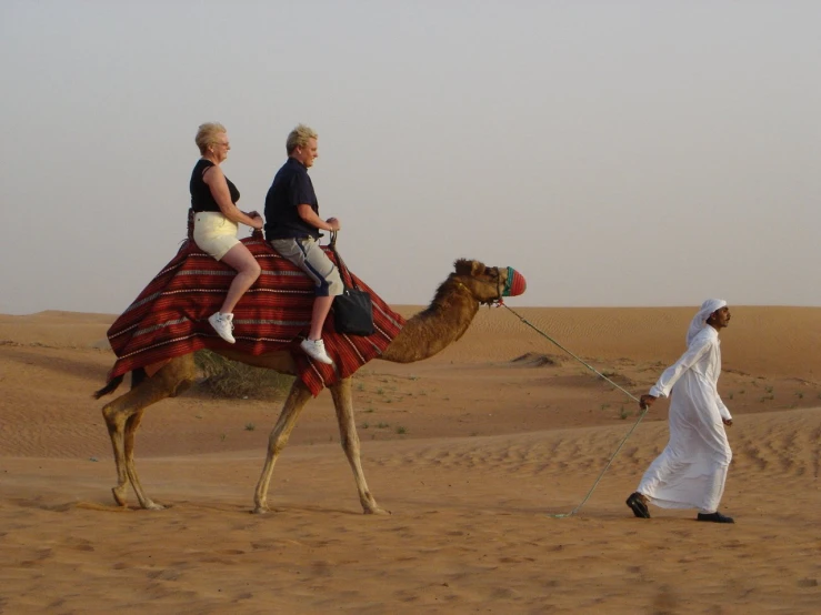 a man and a girl riding on a camel