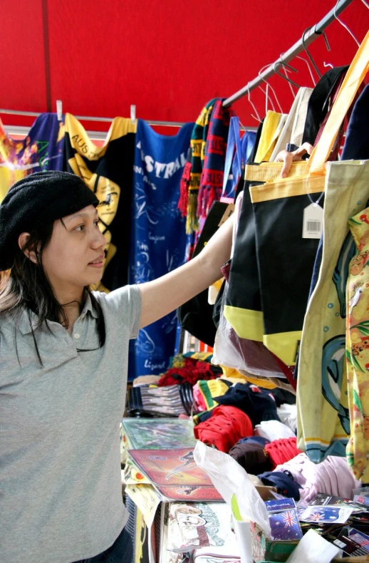 a woman looks at the shirts on sale in an outdoor market