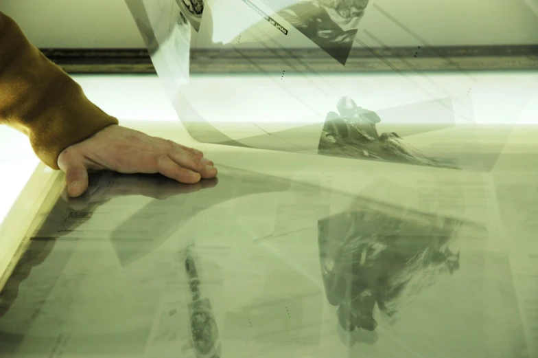 a person leaning against a desk with his hands resting on it