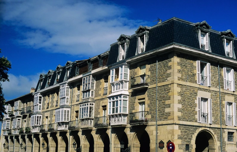 a stone building with multiple balconies and a red street sign in front