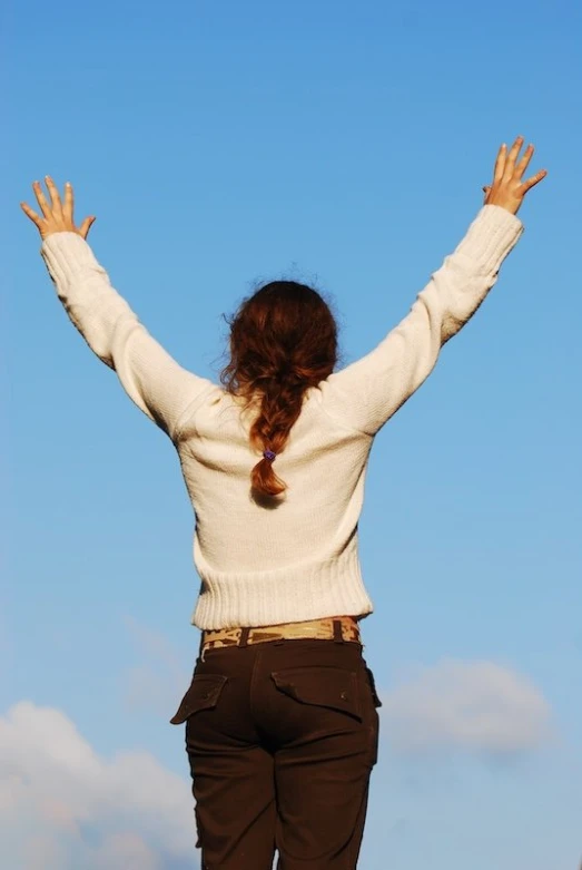 a girl in brown pants and a sweater flying a kite