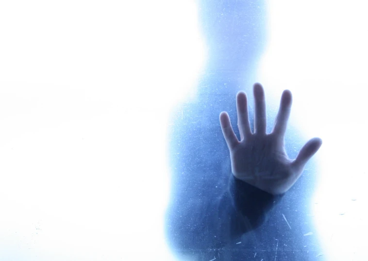 a hand touching a frosty window glass in the sunlight