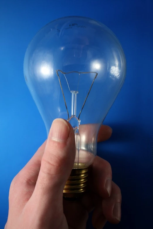 a person holding a light bulb with its fingers