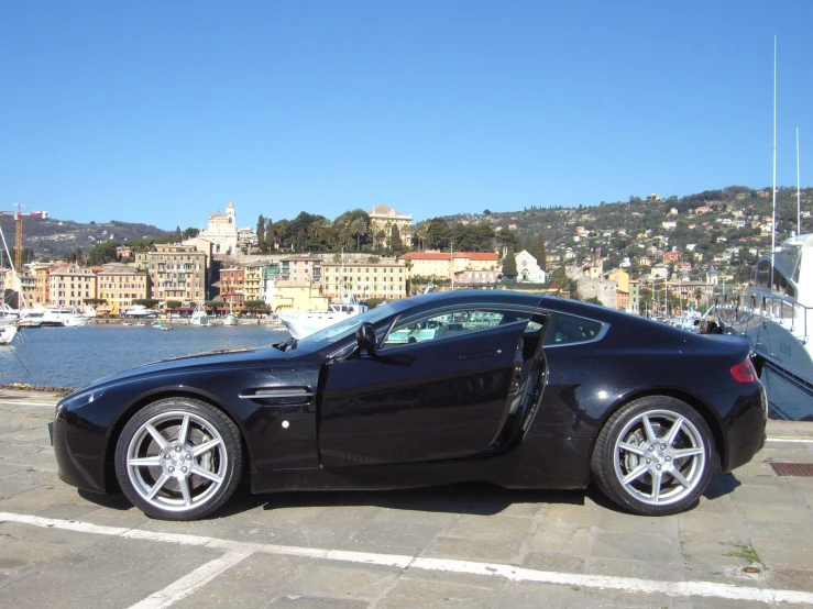 a dark colored sports car parked in front of some boats