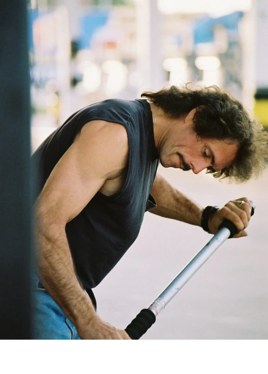 a man with long hair is leaning against a pole