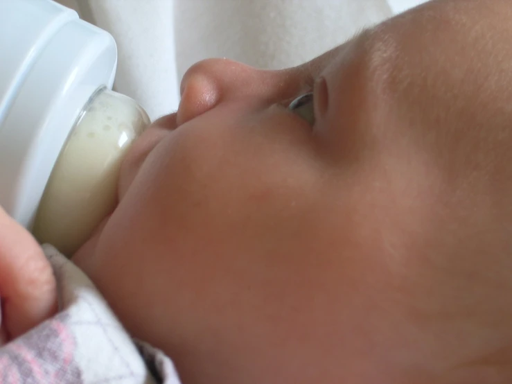 the baby is drinking from a sippy bottle