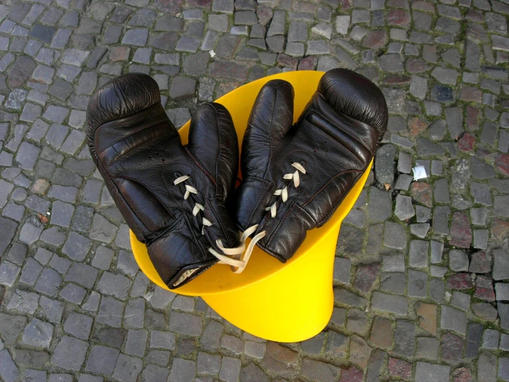 a pair of black leather boots sitting on a yellow plastic stool