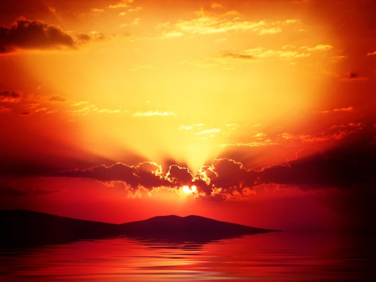 a bright yellow, orange and red sunset over some mountains