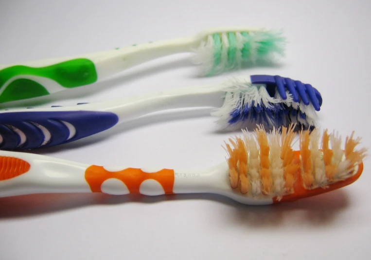 three tooth brushes sitting next to each other on top of a white table