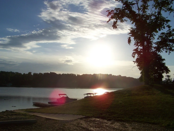 boat on lake shore during sunset with clouds