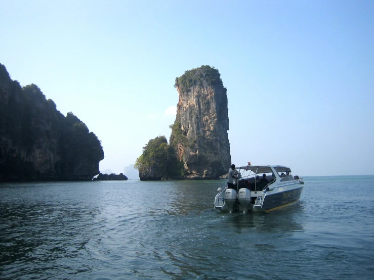 a boat floating on the water near a rock island