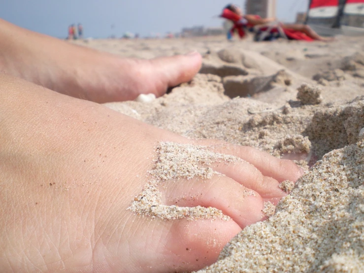 someone's feet are covered in sand on the beach