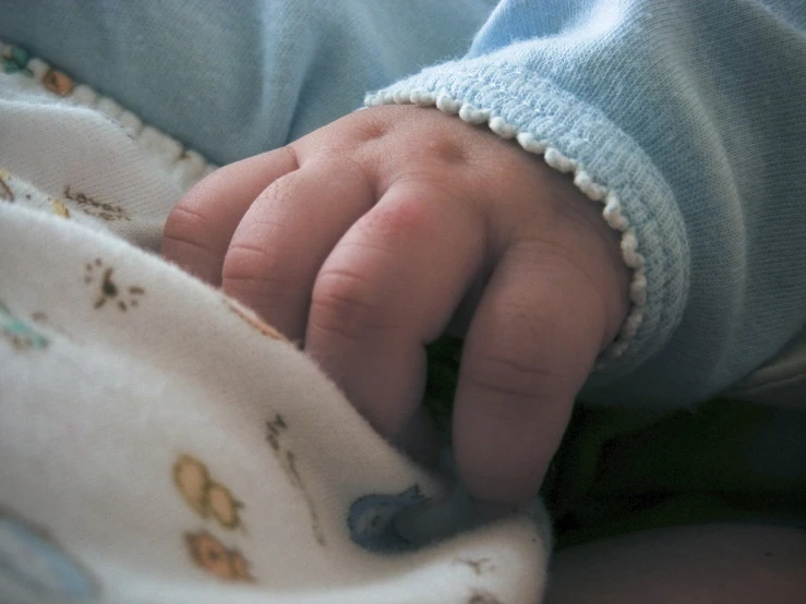 a baby's hand under a blue blanket