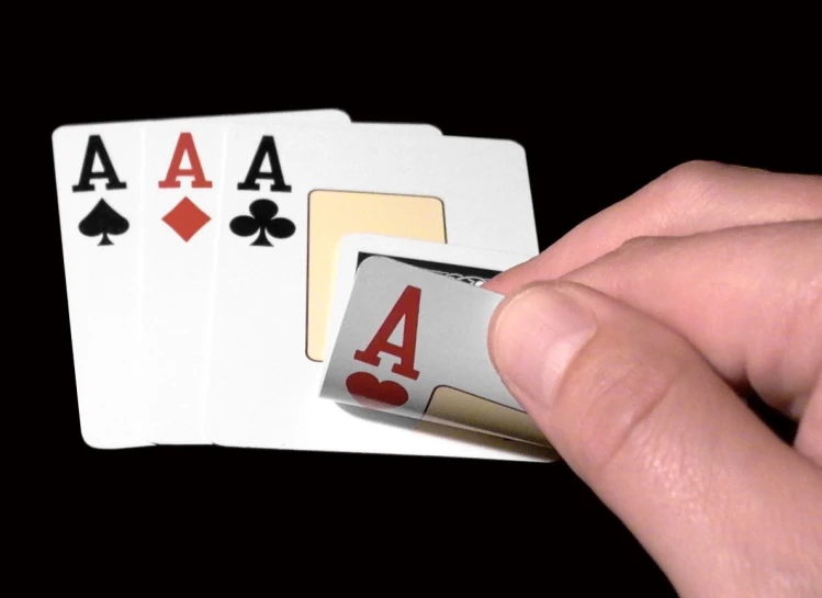 a hand holding four playing cards with one ace