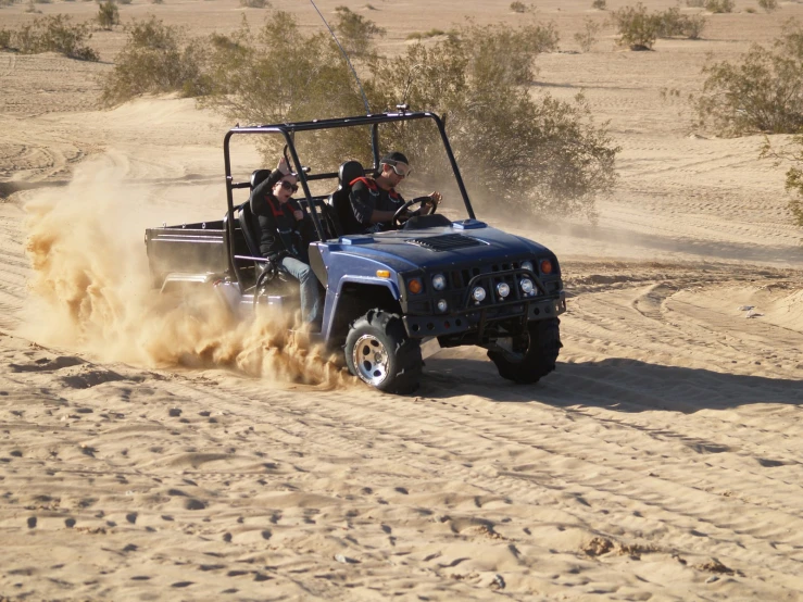 several people in an off road vehicle driving on a desert trail