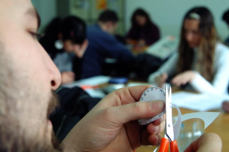 a man with scissors  paper and people sitting behind him