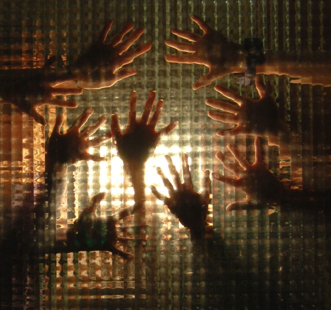 the shadow of several hands coming out of a window