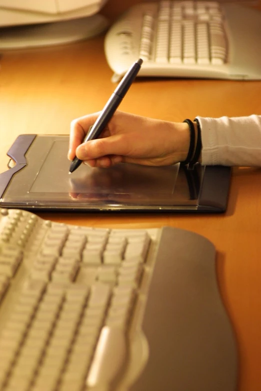 a person is writing on a sheet of paper near the computer keyboard