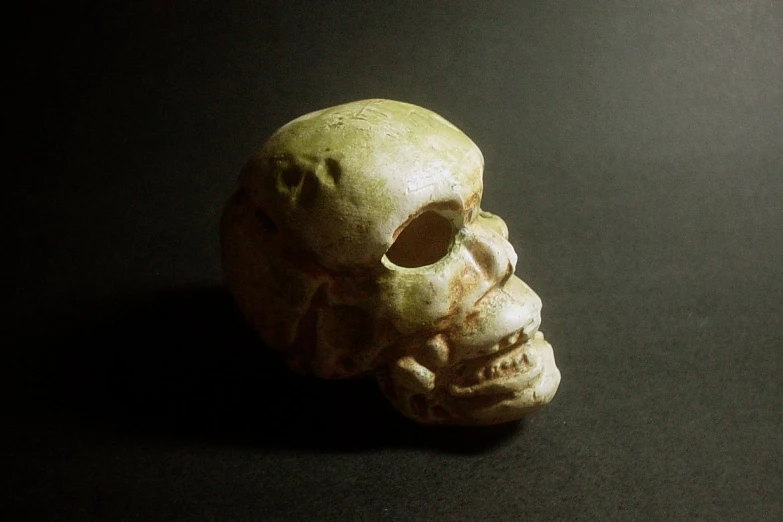 an odd looking clay skull sitting on a black surface
