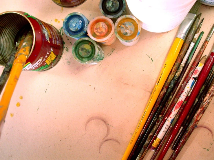 there are some paints, pencils, and water on the table