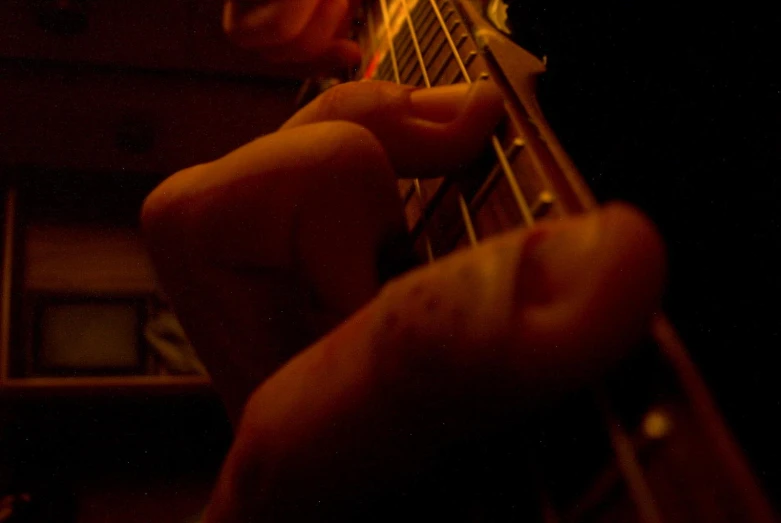 hands with a guitar are playing on the strings