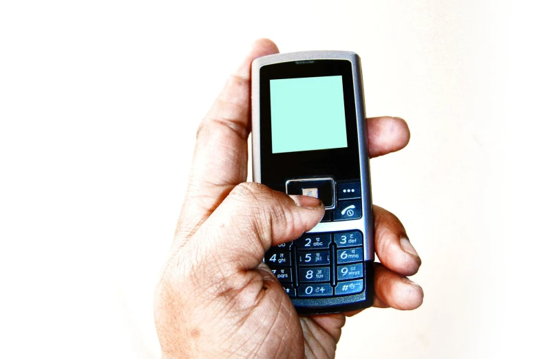 a hand holding an old fashioned cellphone in its left hand