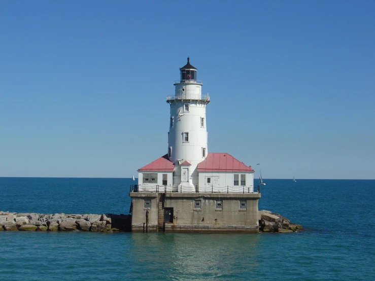 a lighthouse stands on a pier next to the ocean