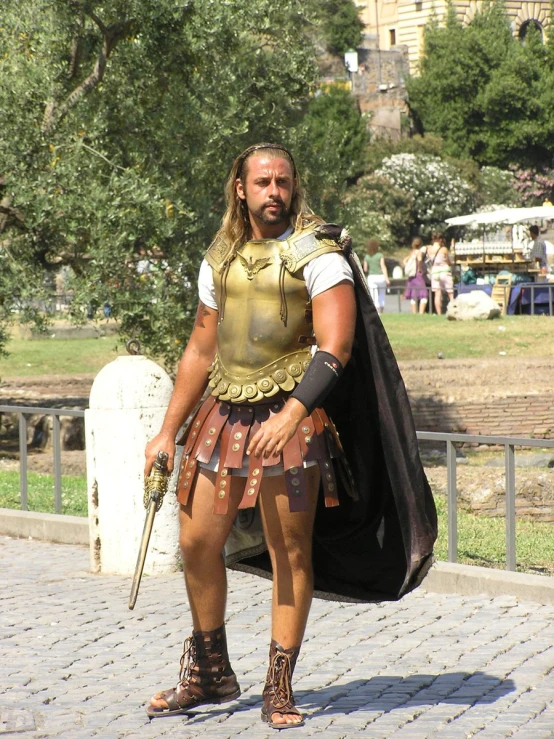 the roman man in the costume is holding a sword