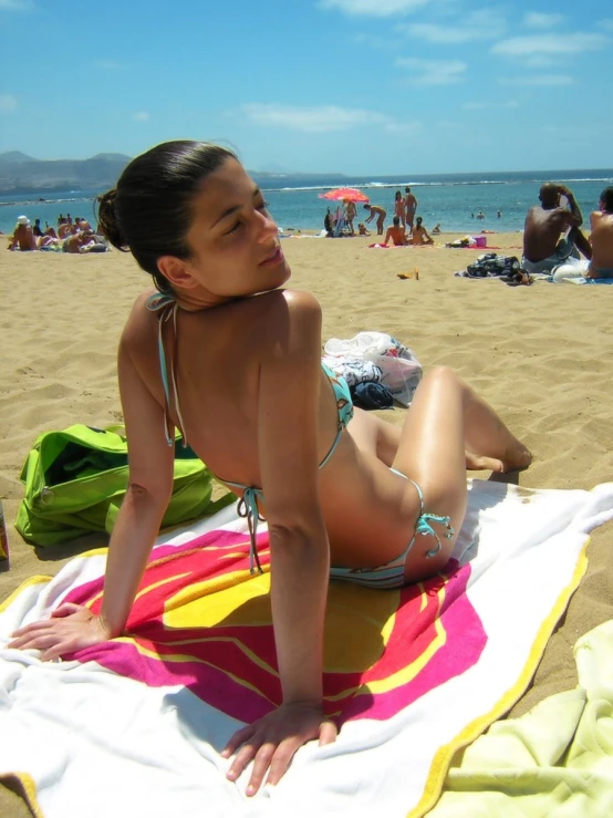 a woman sitting on top of a towel on the beach