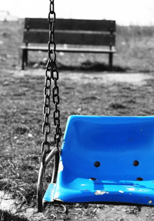 a broken swing and chain sit in a park