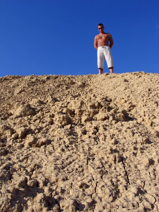 a man standing on top of a sandy hill