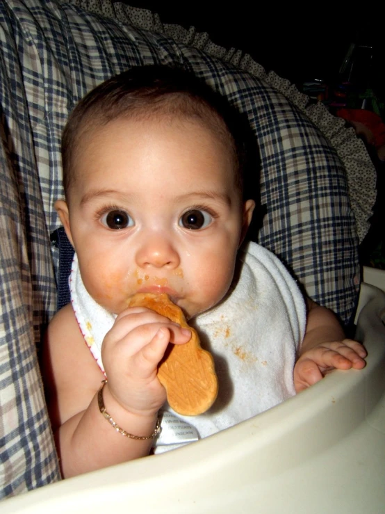 an infant is holding food in its mouth