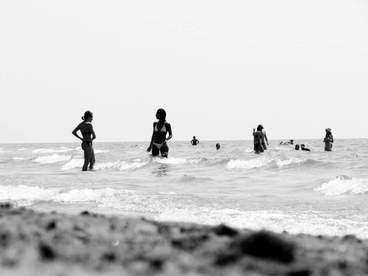 a beach with people swimming and onlookers walking in the water