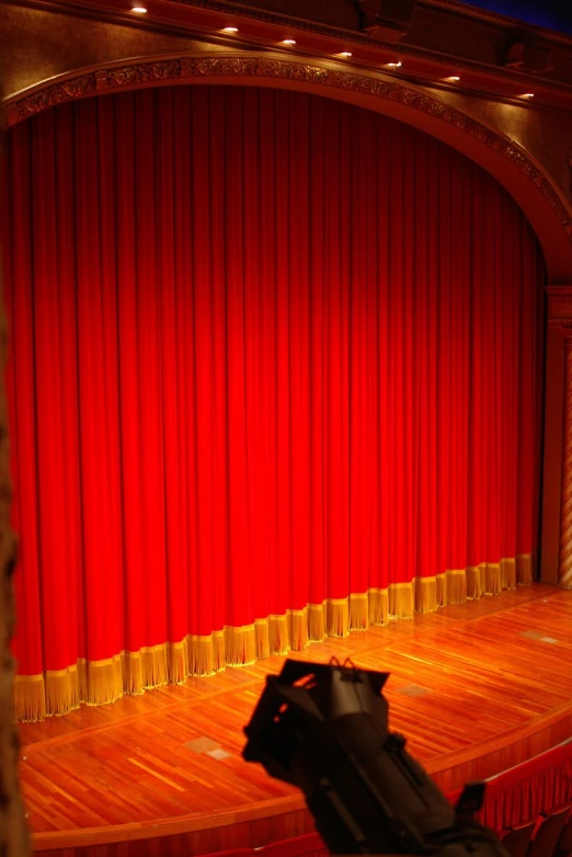 the red curtain is on stage where a black object sits