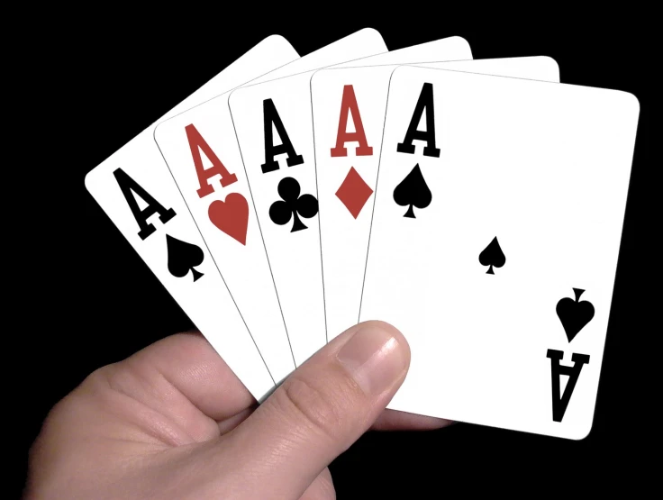 a hand is holding four playing cards