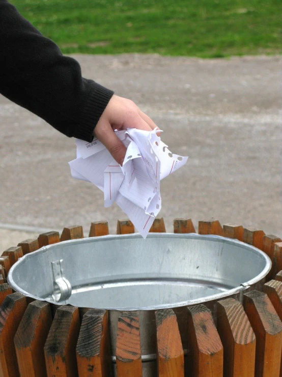 the person's hand is putting some napkins in the trash can