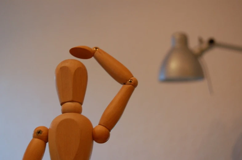 a wooden dummy poses in front of a light