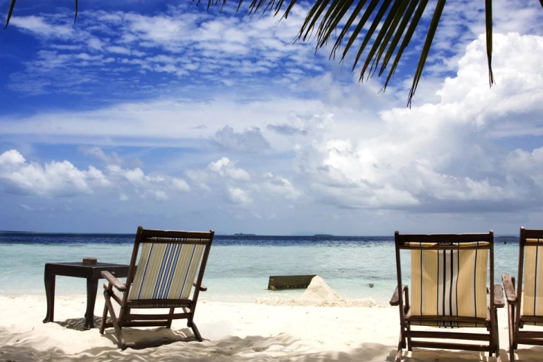 two beach chairs are sitting on the sand in front of the ocean