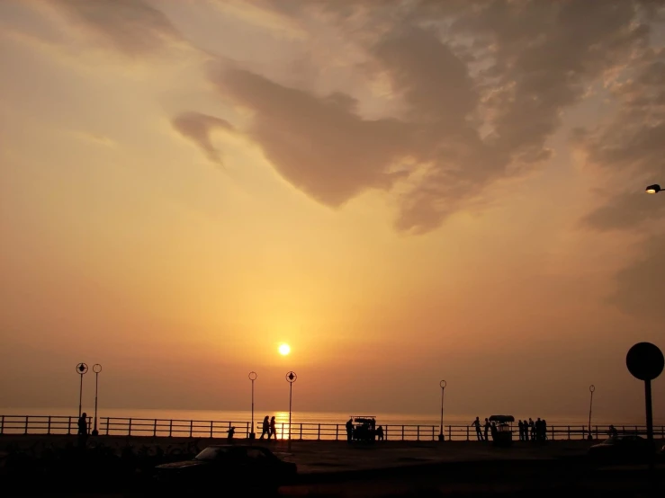 the sun is setting at the beach in front of the pier